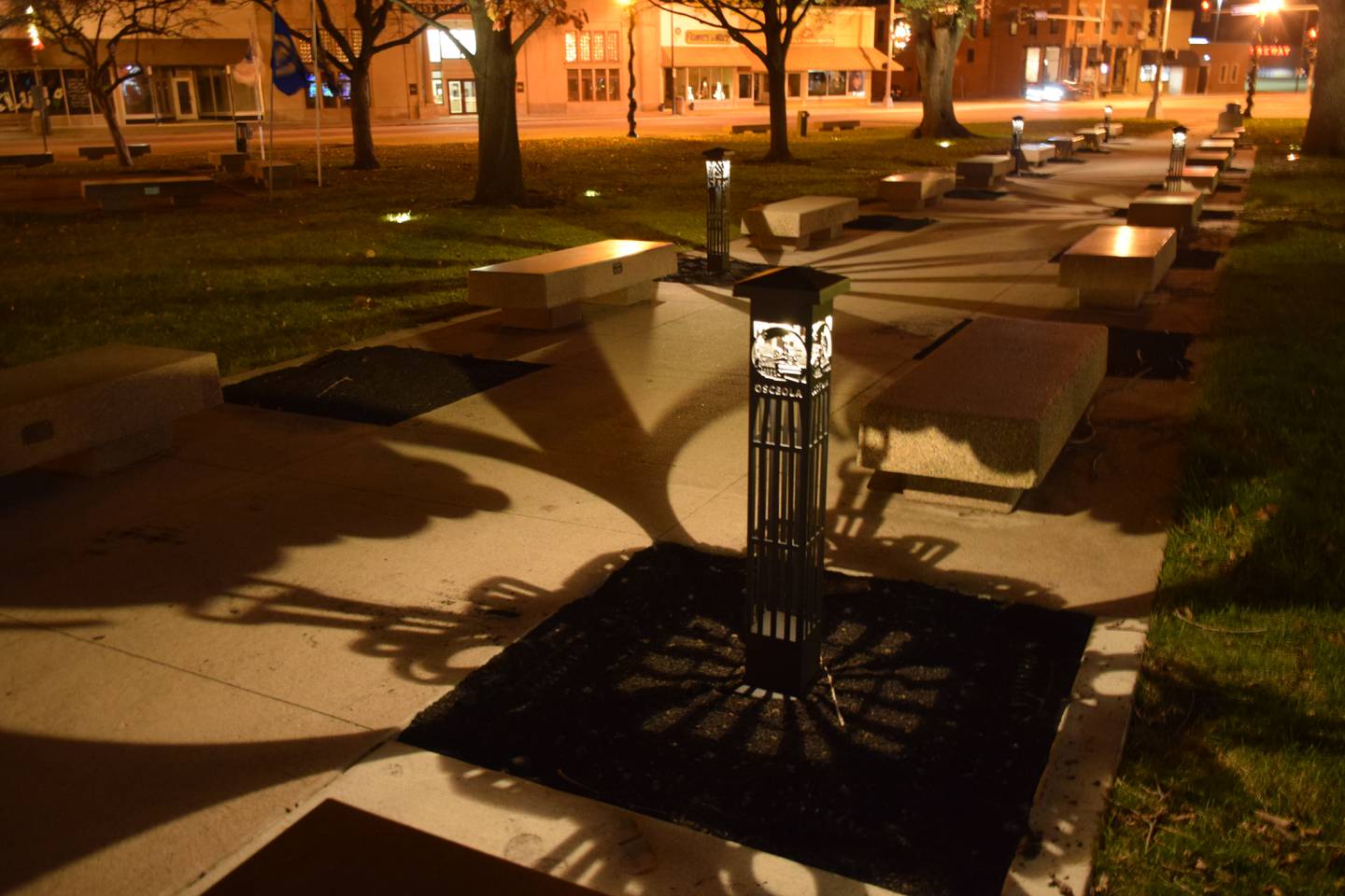 Bollards on the courtyard square emit light through cutouts at night.