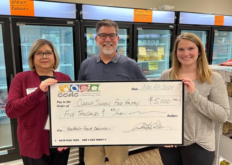 Maribel Torres, left, and Becca Kedley, right, accept a check from Clarke County Development Corporation Executive Director Andrew B. Clark for the Clarke Food Pantry, after the nonprofit organization’s name was drawn during the annual CCDC Nonprofit Forum.