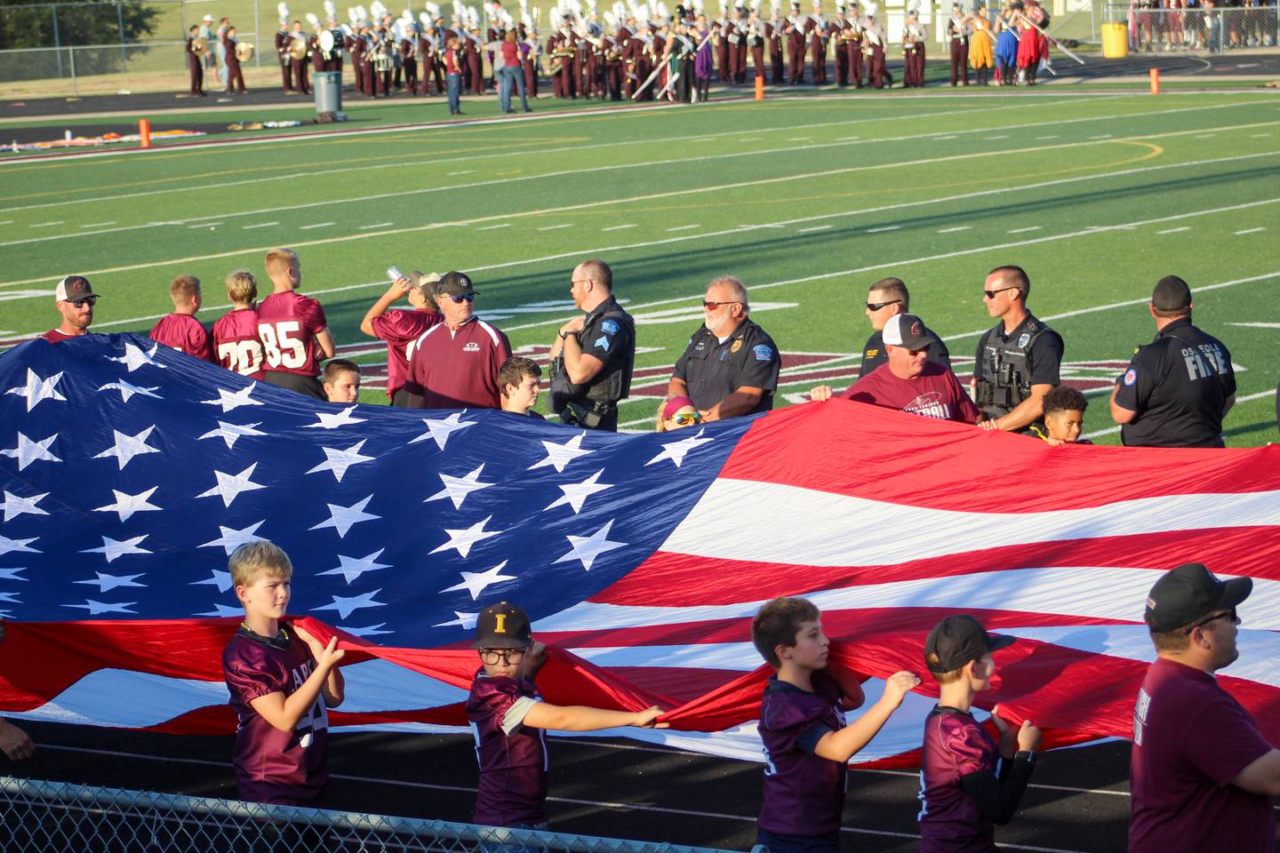Clarke youth football and coaches bring in the American flag.